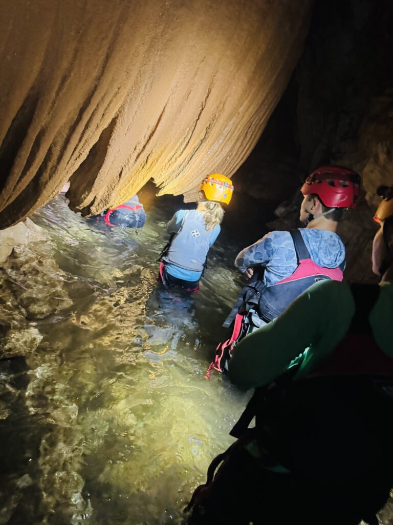 Family hiking through Caves Branch cave system and wading through water