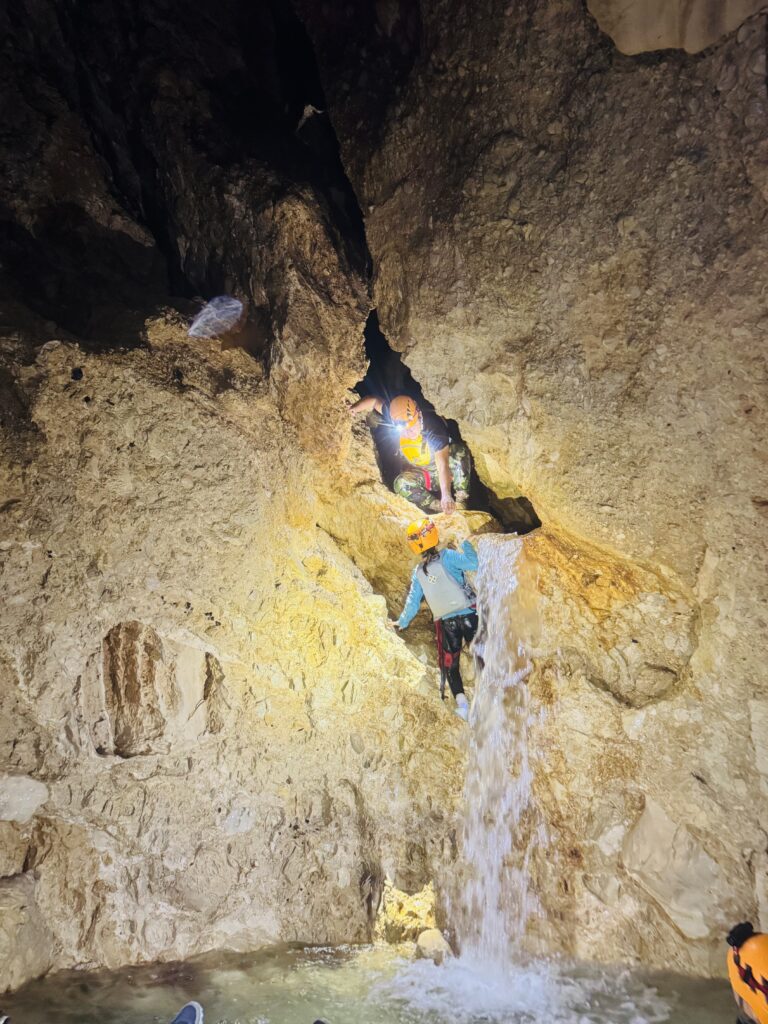 Kids climbing waterfall wall inside Belize cave